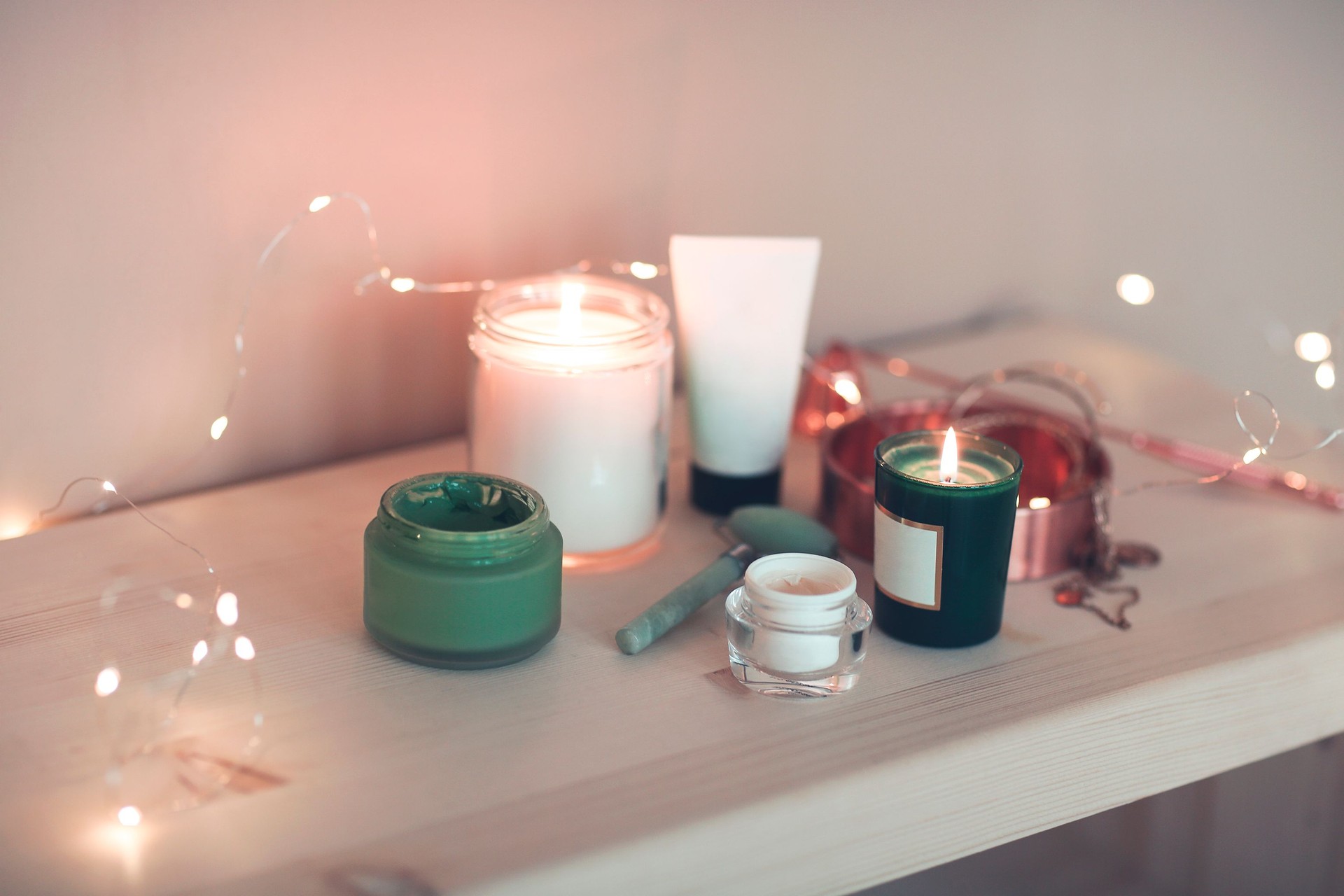 Burning candles and containers with various skincare cosmetics